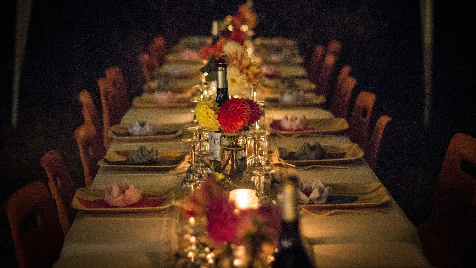 A long dining table set with candles and flowers for an evening dinner celebration